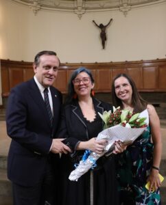 Fotografía del rector Ignacio Sánchez junto a Paulina Rodríguez D. y Karin Friedlie con flores en sus manos