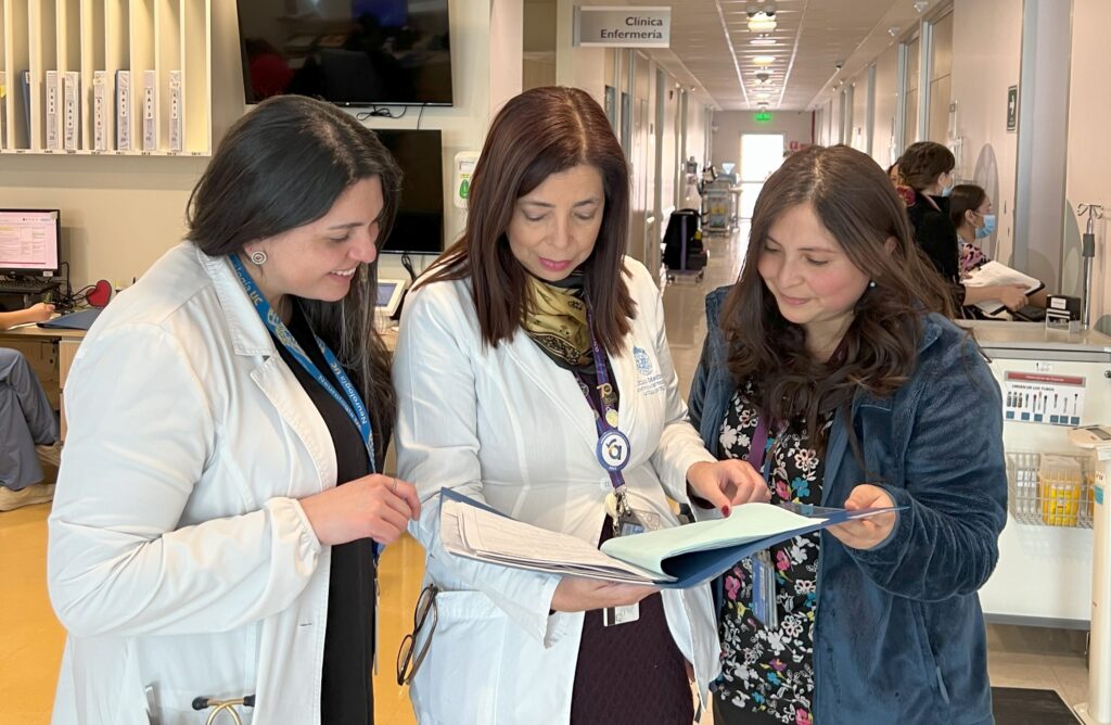 Fotografía de la Dra. Keryma Acevedo junto a dos colegas leyendo un archivo.