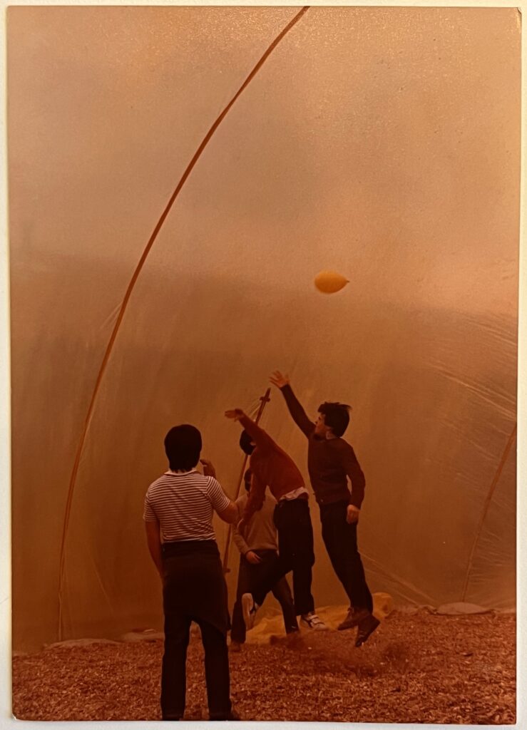 Fotografía de 4 personas de pie sosteniendo unas varillas largas, la foto se ve antigua