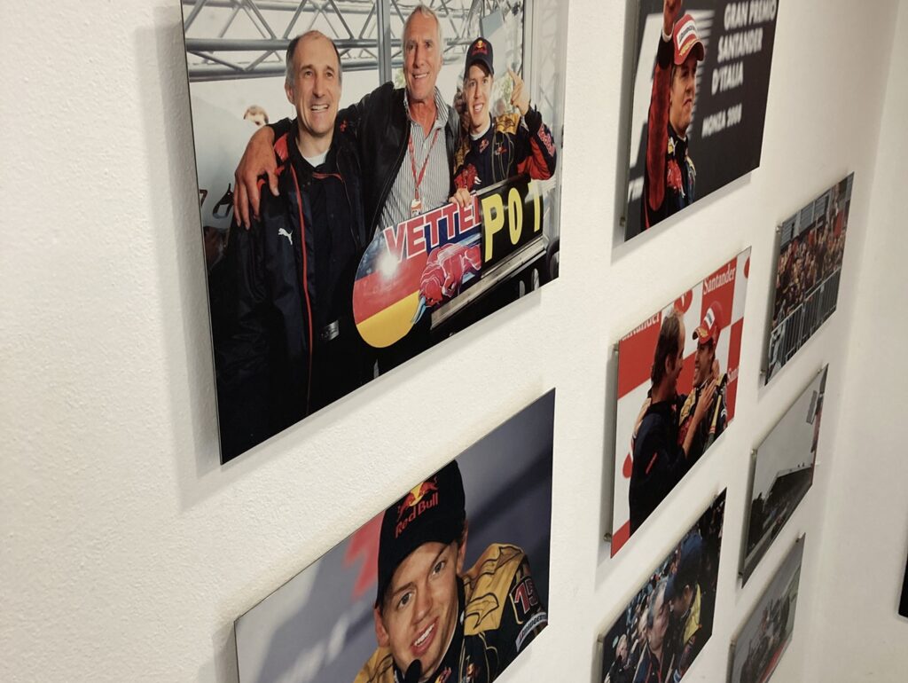 Fotografía de un muro de cuadros con imágenes del recuerdo de la escudería donde se muestra a un joven Sebastian Vettel quien, años después, se consagraría como campeón mundial de la F1)