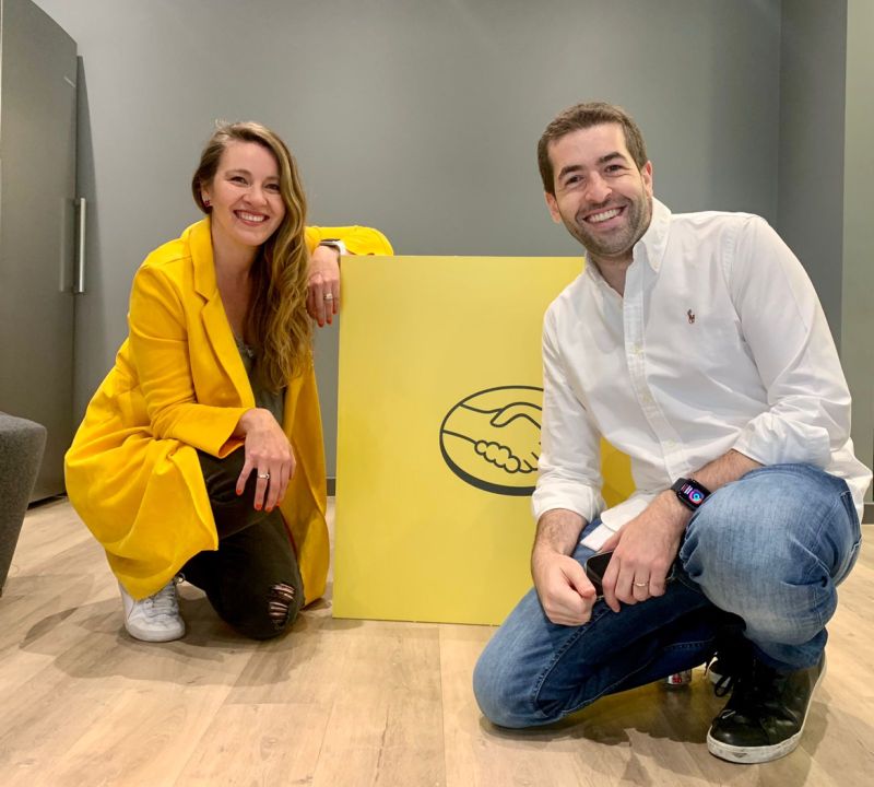 Fotografía de Bernardita Mazo junto a Alan Meyer agachados con un cubo grande con el logo de Mercado Libre
