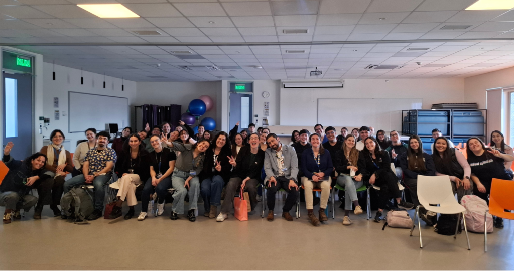 Foto de un grupo de decenas de personas sonriendo y haciendo gestos con las manos